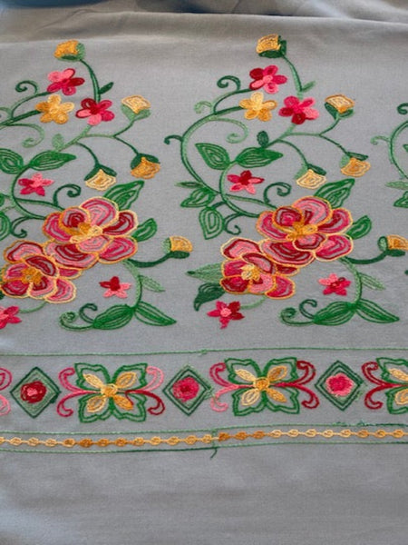 Pink/Gold/Green Embroidery on Sky Blue. Embroidery Runs Along Each Edge of Fabric as a Border