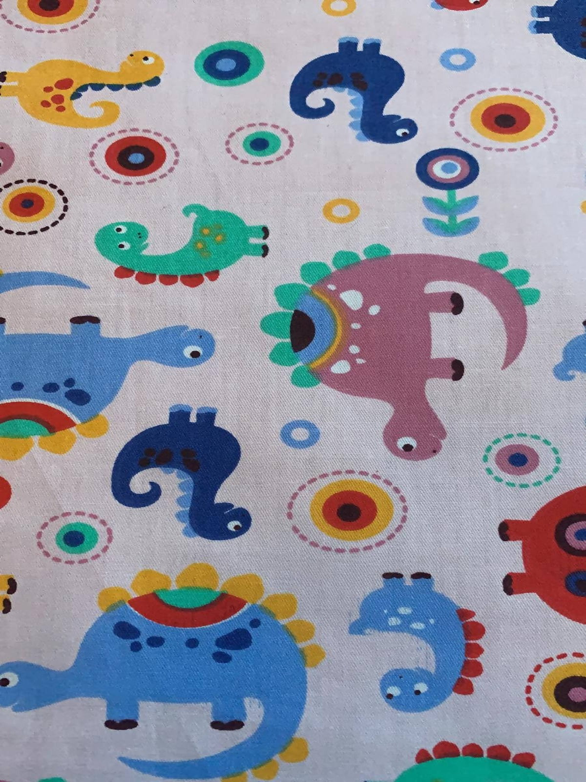 Multi coloured Dinosaurs on pale Pink Cotton Sateen - Deadstock fabric on AmoThreads
