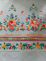 Teal/Gold/Red Embroidery on Sky Blue. Embroidery Runs Along Each Edge of Fabric as a Border