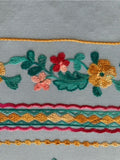 Teal/Gold/Red Embroidery on Sky Blue. Embroidery Runs Along Each Edge of Fabric as a Border