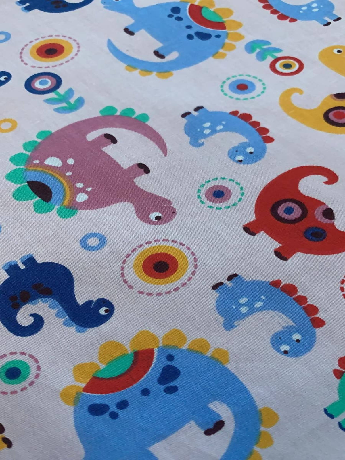 Multi coloured Dinosaurs on pale Pink Cotton Sateen - Deadstock fabric on AmoThreads