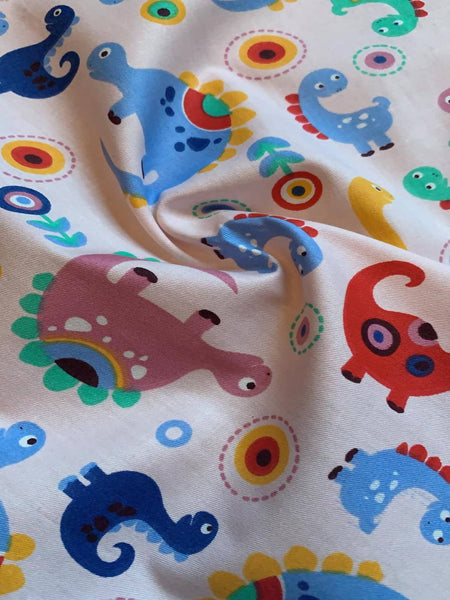 Multi coloured Dinosaurs on pale Pink Cotton Sateen - Deadstock fabric on AmoThreads